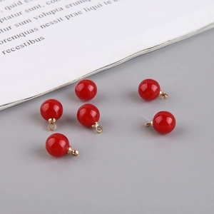 Close-up of six glossy red round beads with gold metal loops for DIY jewelry making