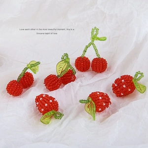 Close-up of handmade beaded red cherry and strawberry charms for DIY jewelry making