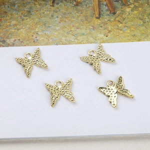 Set mit vier vergoldeten Schmetterlingsanhängern für DIY-Schmuck auf weißer Karte