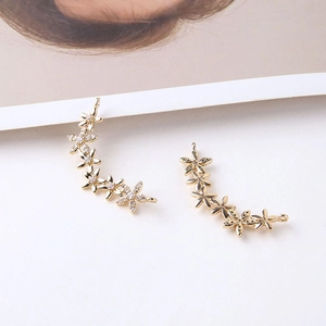 Macro shot of gold floral ear climbers with white cubic zirconia on a white background
