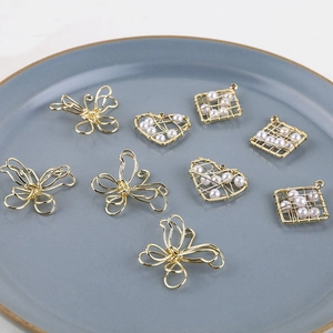 Detalle de dijes de corazón y mariposa en hilo de oro de 18K con perlas en bandeja