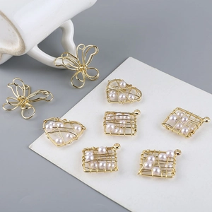 Detalle de colgantes de perlas con forma de corazón y mariposa bañados en oro de 18K