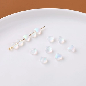 Detailansicht irisierender herzförmiger Glasperlen für DIY-Schmuck auf weißem Tablett