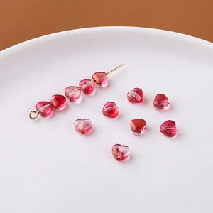 Makro-Detail von herzförmigen Glitzer-Glasperlen mit rosa Verlauf und Goldflocken