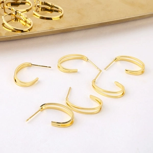 Primer plano de pendientes en C bañados en oro 18K con sello de plata S925
