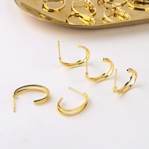 Foto macro de pendientes geométricos en C bañados en oro de 18K con acabado de superficie pulida