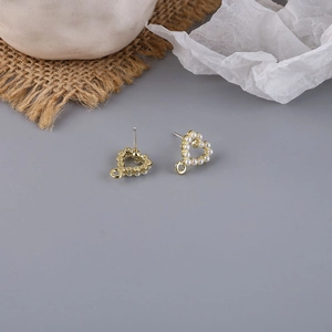 Detail of heart-shaped pearl earrings accessory with gold plating and hanging loop