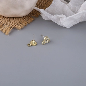 Macro detail of heart-shaped gold-plated earring studs with crystals and DIY loop