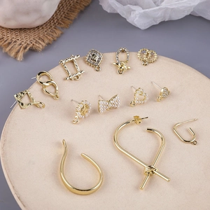 Golden alloy DIY earring charms with pearls, rhinestones, hearts and bows on a tray