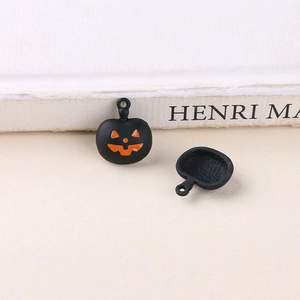 Detailed view of matte black Halloween pumpkin charms with orange Jack-o'-lantern smile