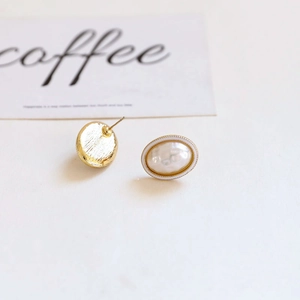 Detailed view of baroque pearl stud earrings with white enamel and golden metal base