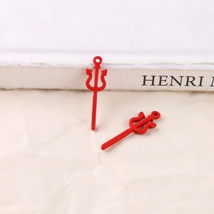 Close-up of red alloy trident charms for Halloween DIY jewelry making on white paper