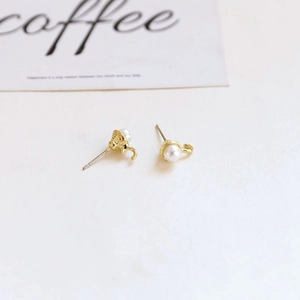Detail view of Baroque pearl earrings with golden C-shape hooks and silver pins