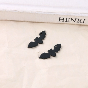 Detailed view of matte black bat pendants for DIY jewelry making on textured background