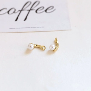 Close-up of J-shaped gold-plated alloy earring charms with pearls for DIY jewelry making
