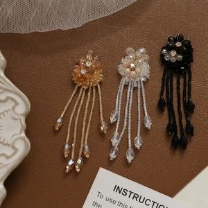 Elegant beaded flower tassel earrings in champagne and black on vintage leather background