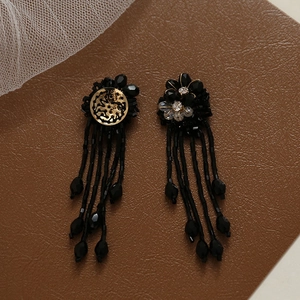 Detailed view of handmade black beaded flower earrings with fringe and gold base