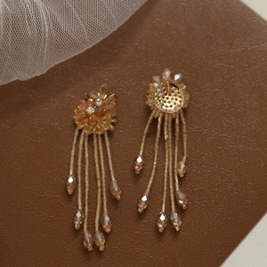 Detail of amber beaded flower earrings featuring crystal tassels and drop pendants