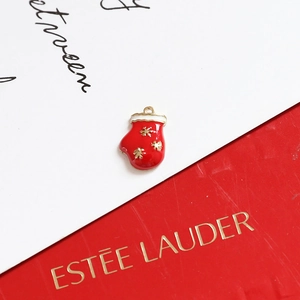 Detailed shot of Christmas glove charm with red enamel finish and golden snowflakes