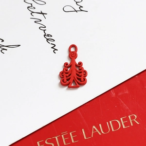 Macro shot of red Christmas tree pendant with cutout filigree and metallic finish