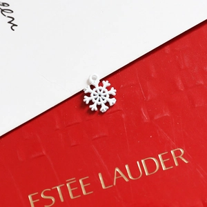 Macro shot of white snowflake charm pendant with detailed festive spray paint finish