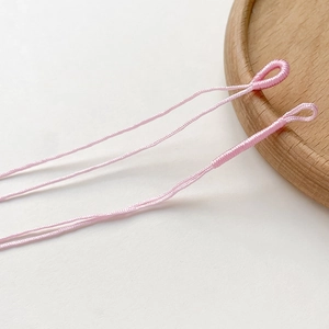 Makroaufnahme einer fein handgewebten rosa Schmuckschnur-Schlaufe mit Satinstruktur