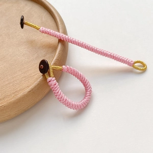 Detailed close-up of pink and gold handmade braided rope knot with a brown button clasp