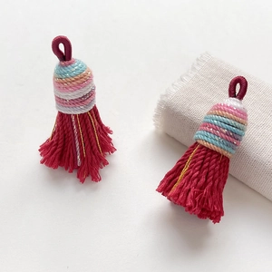 Close-up of deep red braided tassels with colorful glitter threads for DIY craft jewelry