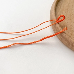 Makro-Detail hellorangefarbener geflochtener Nylonschnüre mit Schlaufen für DIY-Schmuck