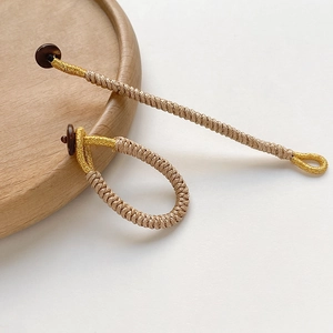 Detail of handcrafted gold and beige braided cord charms with brown button fasteners