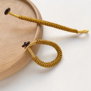 Detailed view of handmade golden silk knotted loop and button with braided textures