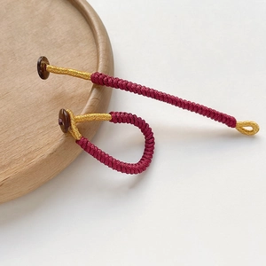 Detail of handcrafted spiral woven cord with dark red and gold thread with button closure