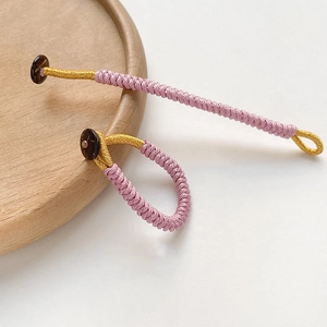 Macro view of handmade purple braided rope ring with gold silk thread detail and button