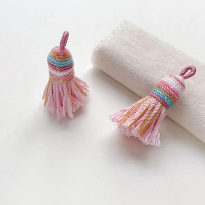 Detail of handmade ethnic tassel pendant with multicolor braided knot and pink silk fringe