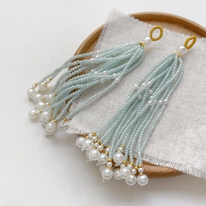 Detailed close-up of handmade beaded tassel earrings with seafoam green beads and pearls