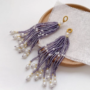 Macro shot of handmade beaded tassels with lavender seeds, white pearls and gold wire