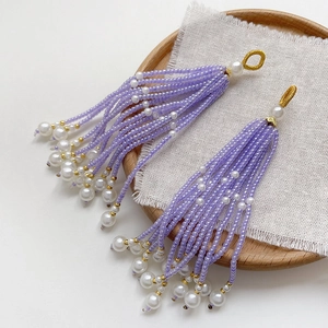 Detail of handmade lavender seed bead and white pearl tassel pendant on rustic wood