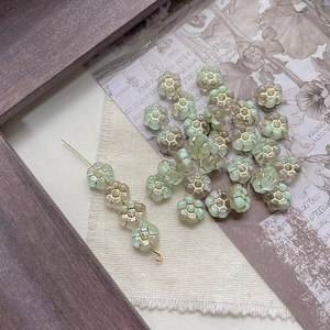 Macro detail of mint and champagne flower glass beads with gold edges for DIY jewelry