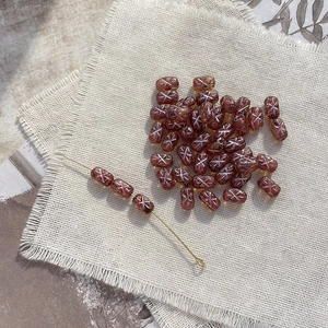 Macro detail of amber glass fish-shaped beads with silver X pattern for DIY jewelry