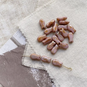 Macro detail of fish-shaped glass beads with purple glaze and gold sand textures