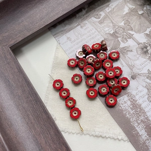 Detailed macro view of vintage red Czech glass flower beads with golden edges and center