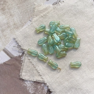 Macro detail of tulip-shaped Czech glass beads in gradient green with iridescent shine