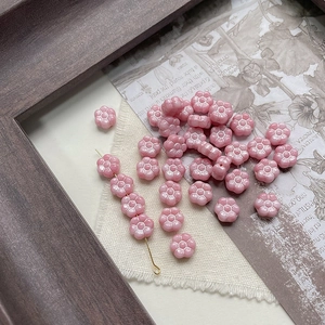 Detailed view of pink Czech glass flower beads on vintage newspaper for DIY craft