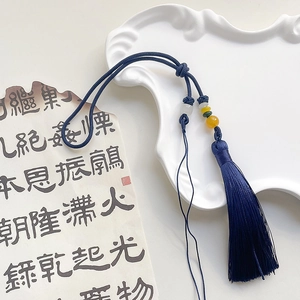 Detail of dark blue silk tassel with jade beads on vintage calligraphy paper