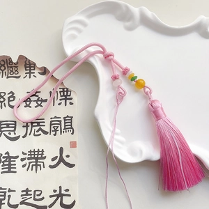 Detailed view of a handmade pink ice silk tassel with decorative beads on a vintage background