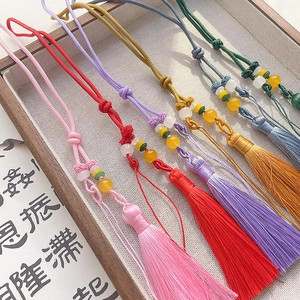 Detail of handcrafted silk tassels with Chinese knots in six colors on a wooden tray