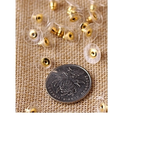 Fermoirs de boucles d'oreilles en silicone transparent avec insert doré près d'une pièce