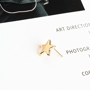 Macro shot of gold star-shaped earrings with polished finish on a white background