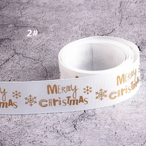 Vista macro di nastro grosgrain bianco con scritte Merry Christmas dorate e fiocchi