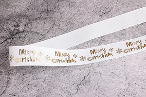 Dettaglio di nastro in gros-grain bianco con scritte dorate Merry Christmas e fiocchi